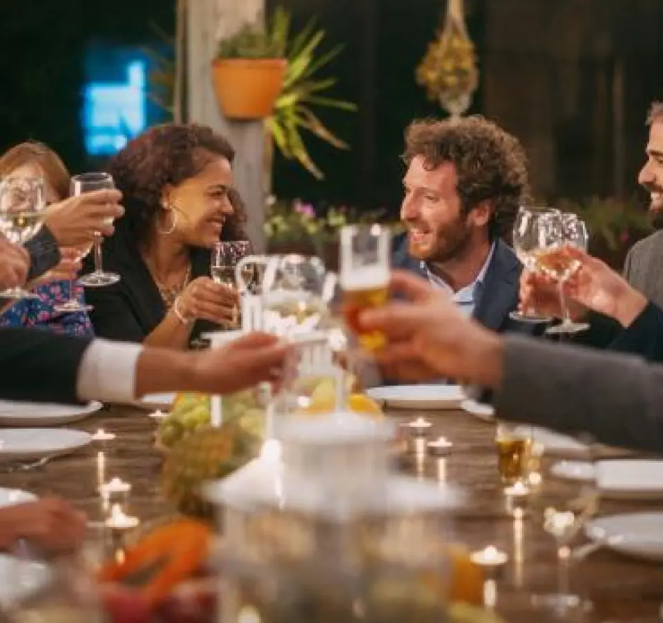 Male and female friends dining at a golf course, smiling and toasting together