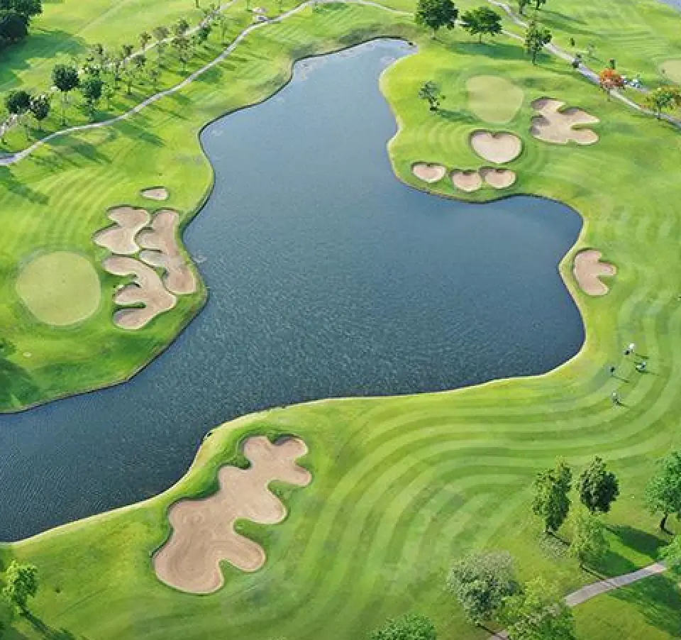 Aerial view of a golf course with green fairways and a bunker