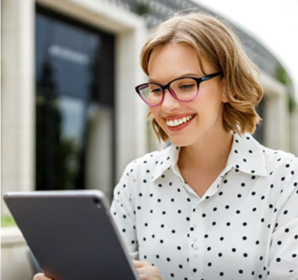 Woman in glasses and polka-dotted shirt using a tablet